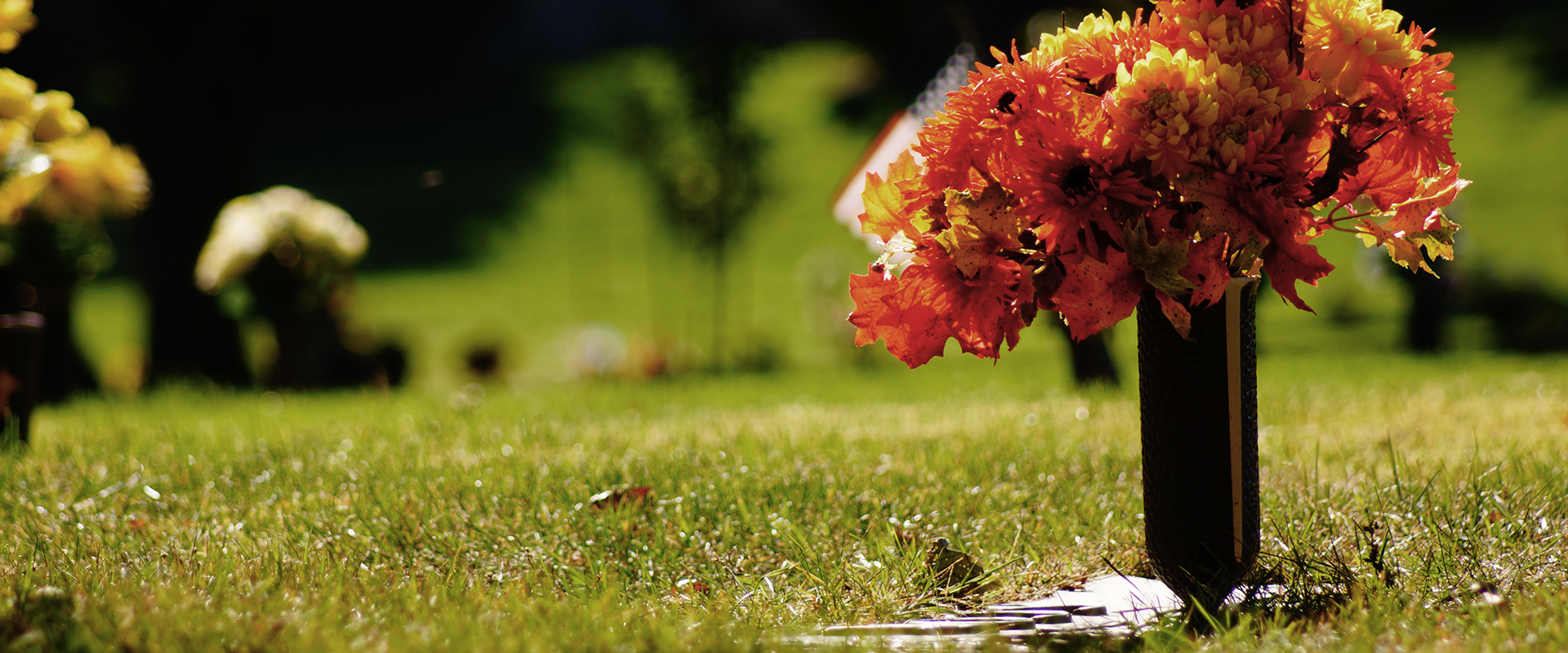 Tumba con ramo de flores rojas y amarillas en un cementerio parque 